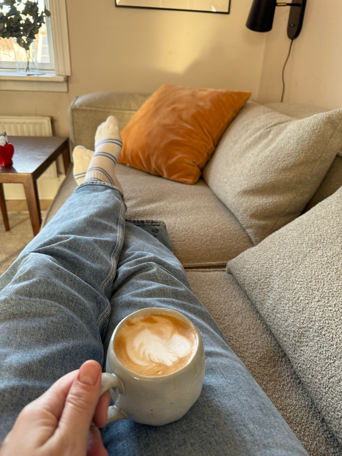 Moment de calme sur un canapé beige, une tasse de café latte à la main