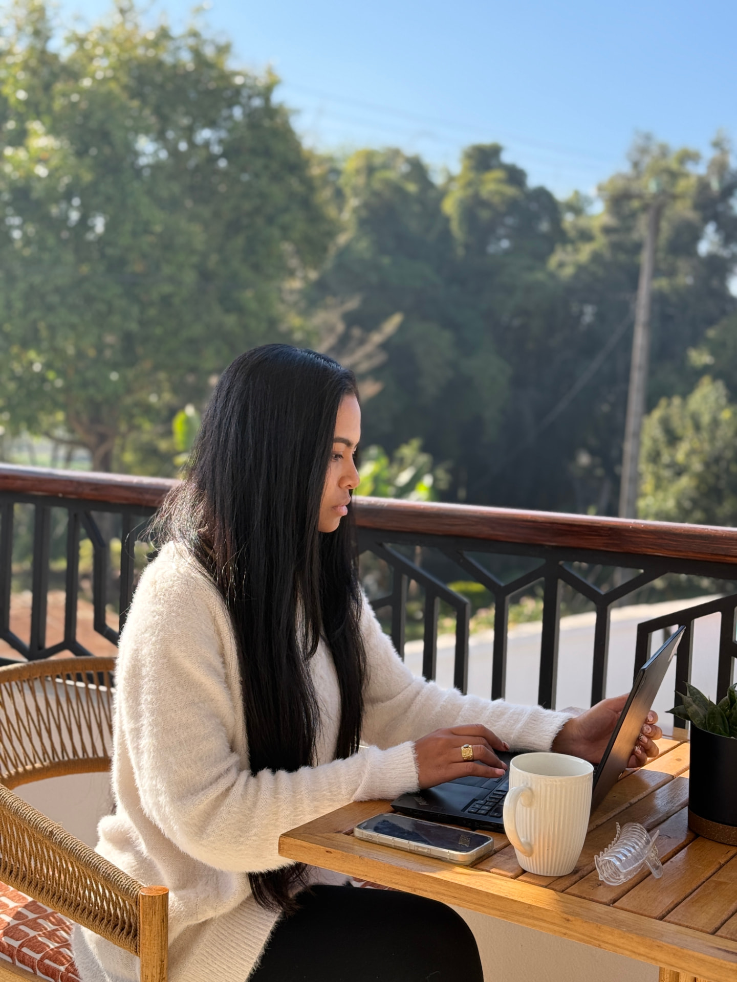 Alicia, assistante virtuelle, travaille sereinement sur son ordinateur en terrasse